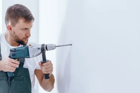 Homem Segurando uma Ferramenta de Perfuração, Furando a parede