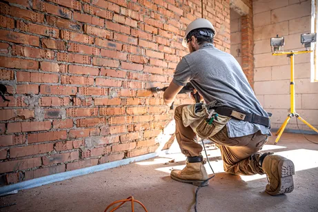 Homem na construção de frente para um muro